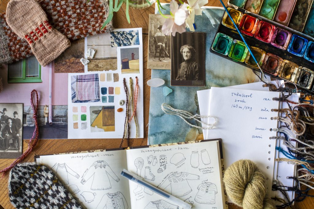 Moodboard med skisser, garn, akvarellfärger och lite stickade verk.