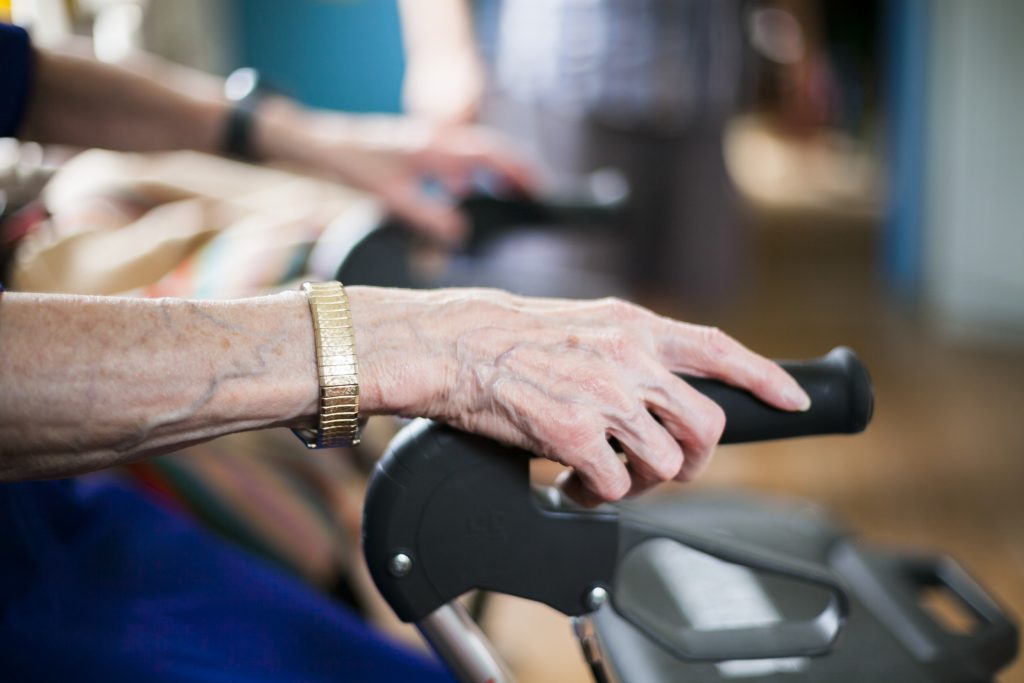 Närbild på äldre kvinnas händer som håller på rullator.